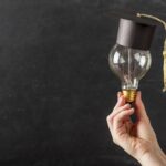 Hand som håller glödlampa med studentmössa på