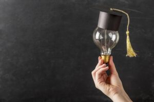 Hand som håller glödlampa med studentmössa på