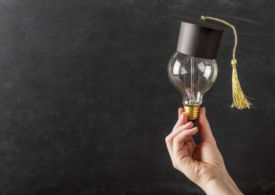 Hand som håller glödlampa med studentmössa på
