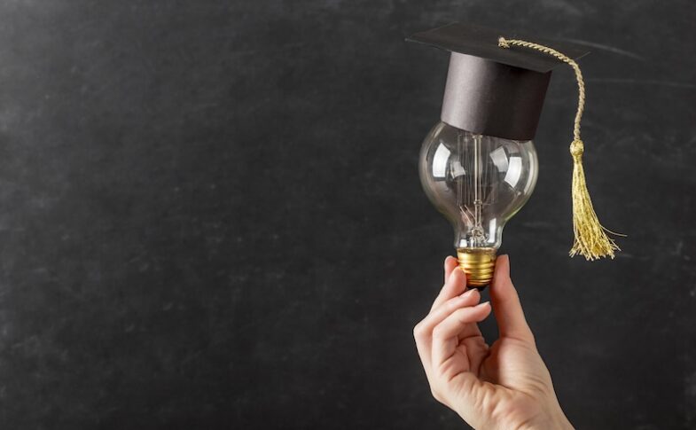 Hand som håller glödlampa med studentmössa på